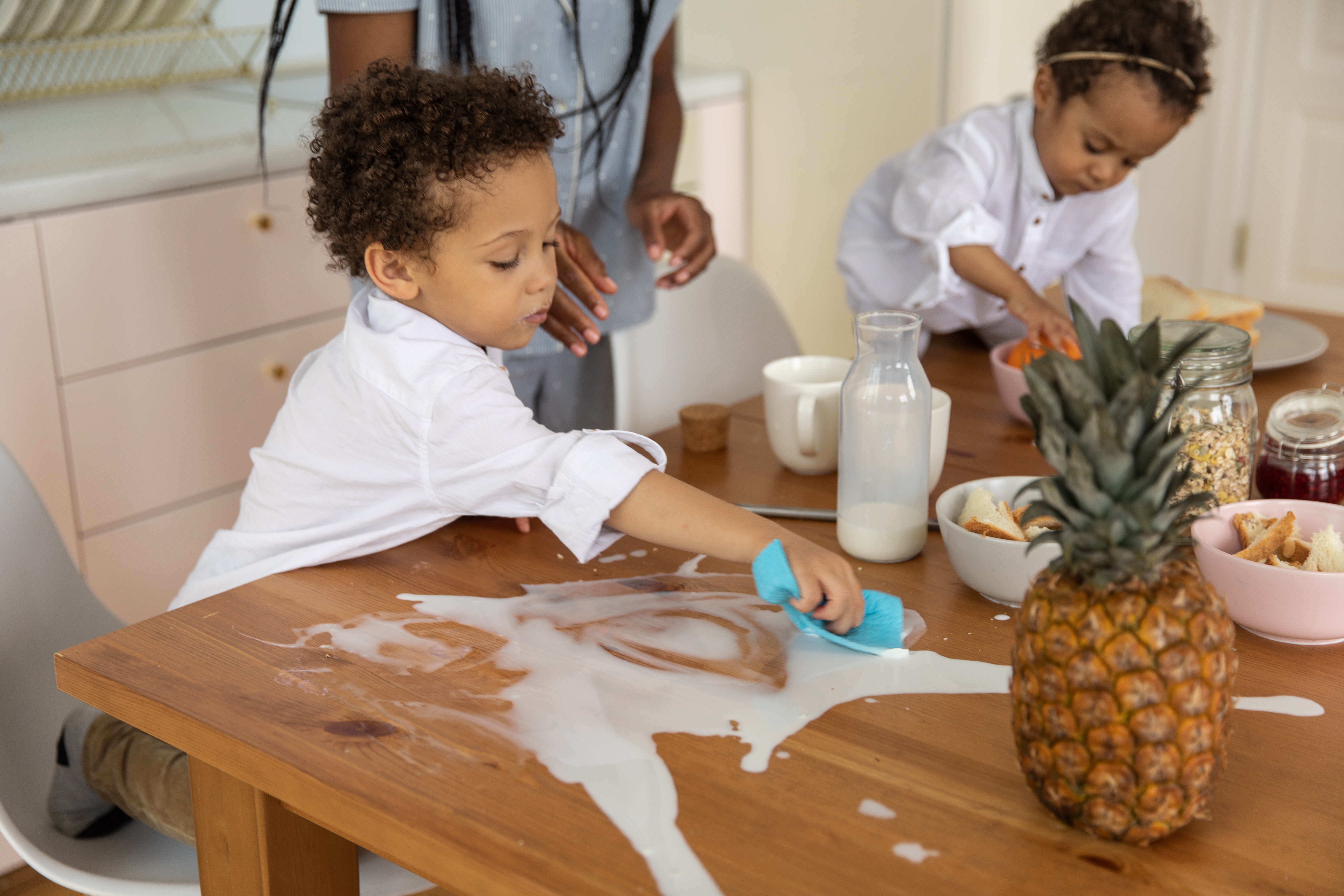 A Boy Wiping the Milk Spillage on the Table